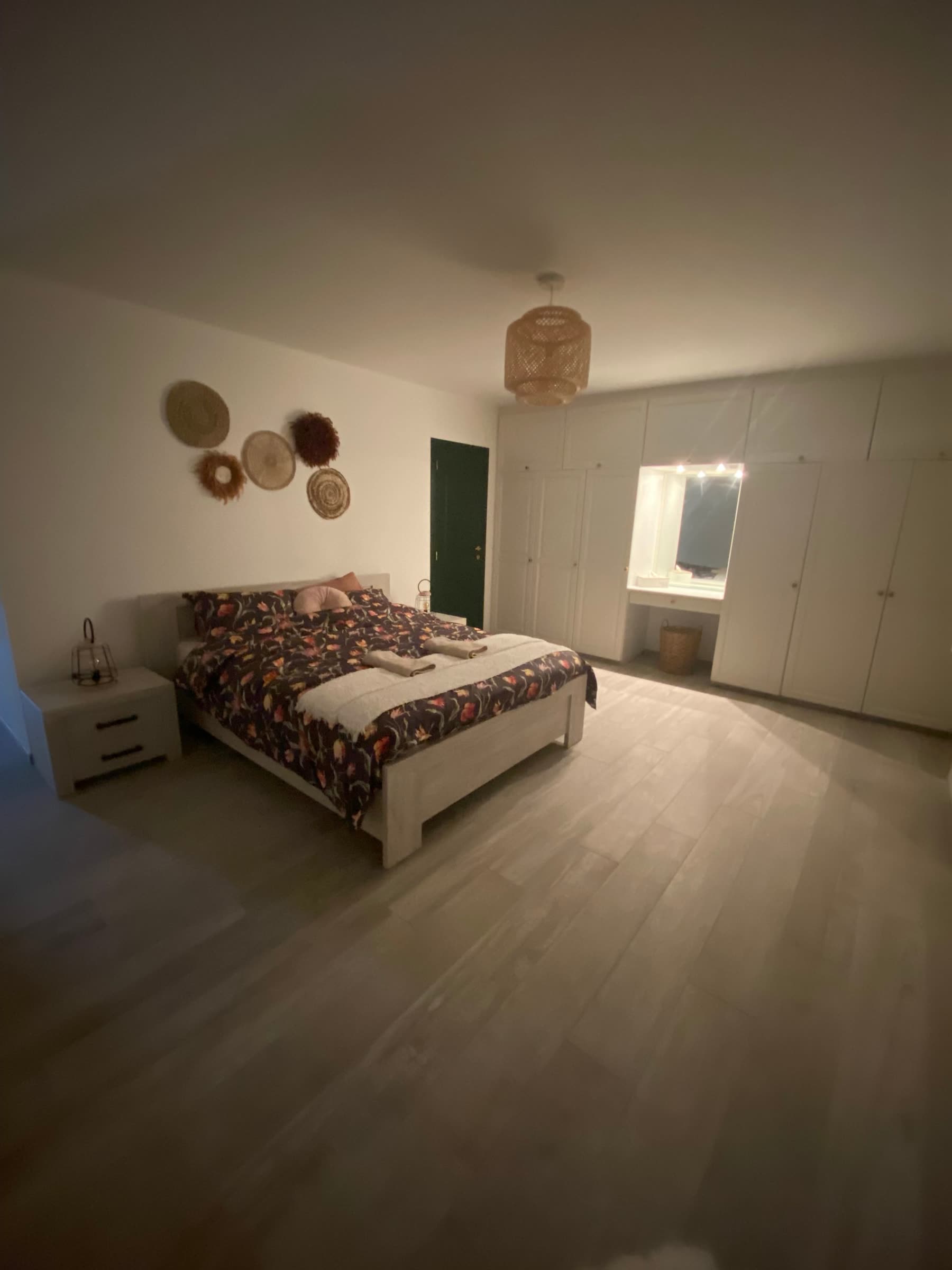 Chambre 1 de La Porte de l'Ardenne : lit double dans une grande pièce claire, paniers muraux en fibres naturelles