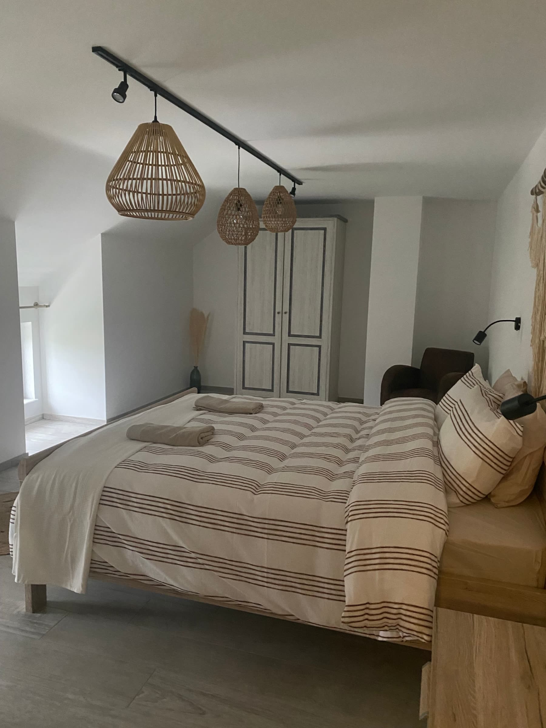 Chambre 3 de La Porte de l'Ardenne : lit double, armoire et suspensions en rotin sous rampant
